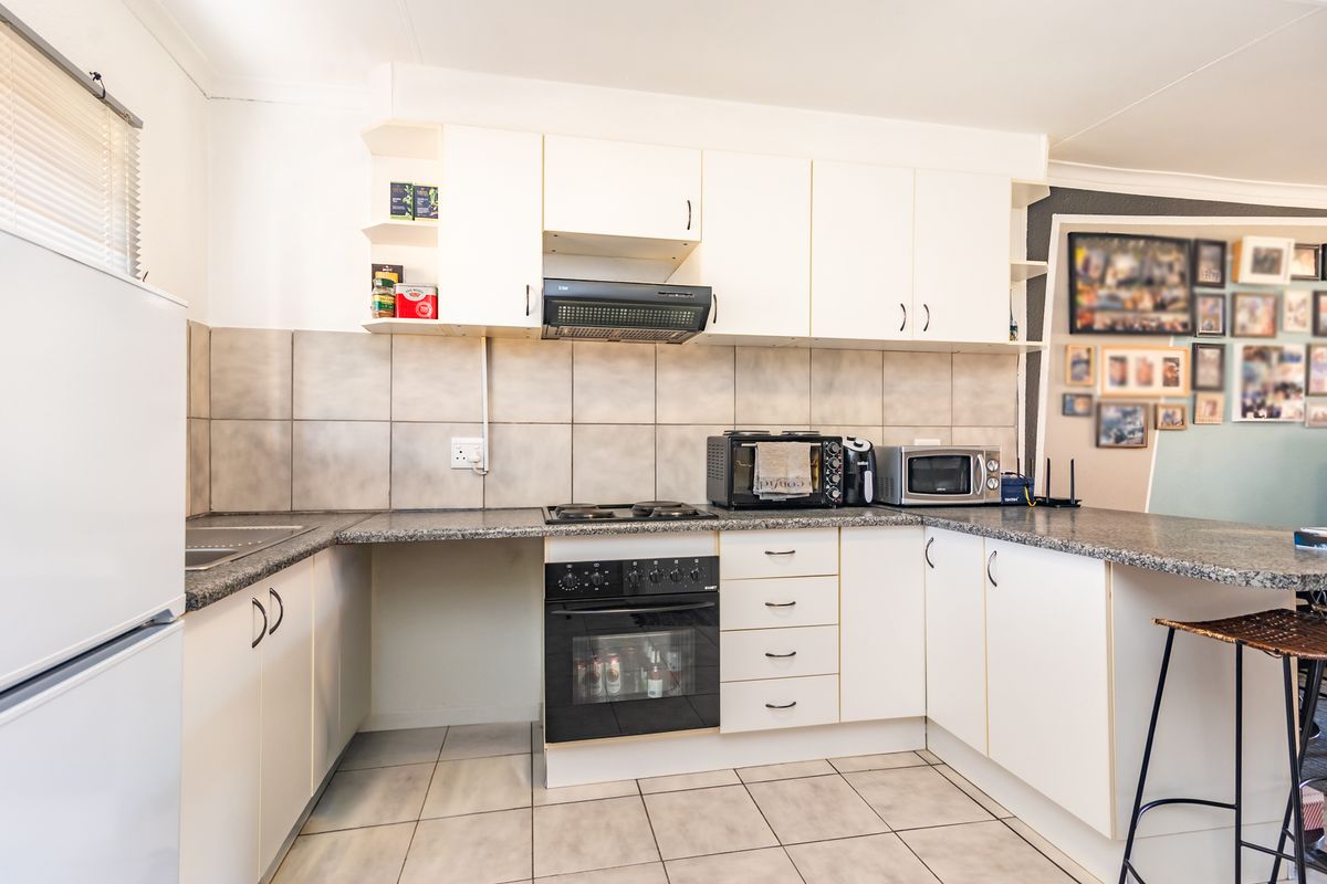 Functional kitchen featuring white cabinetry, granite countertops, a built-in oven with gas hob, and tiled flooring.
