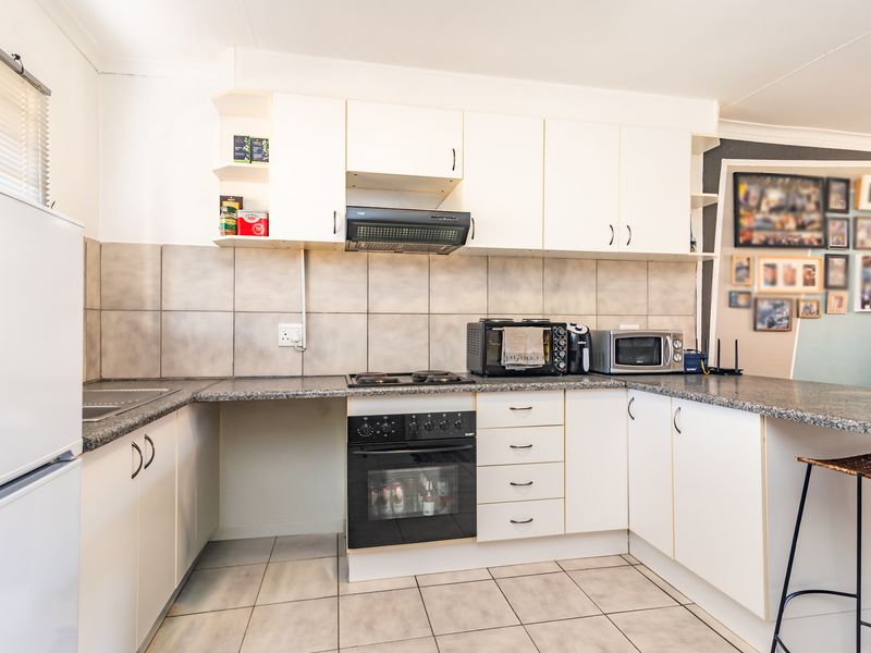 Functional kitchen featuring white cabinetry, granite countertops, a built-in oven with gas hob, and tiled flooring.