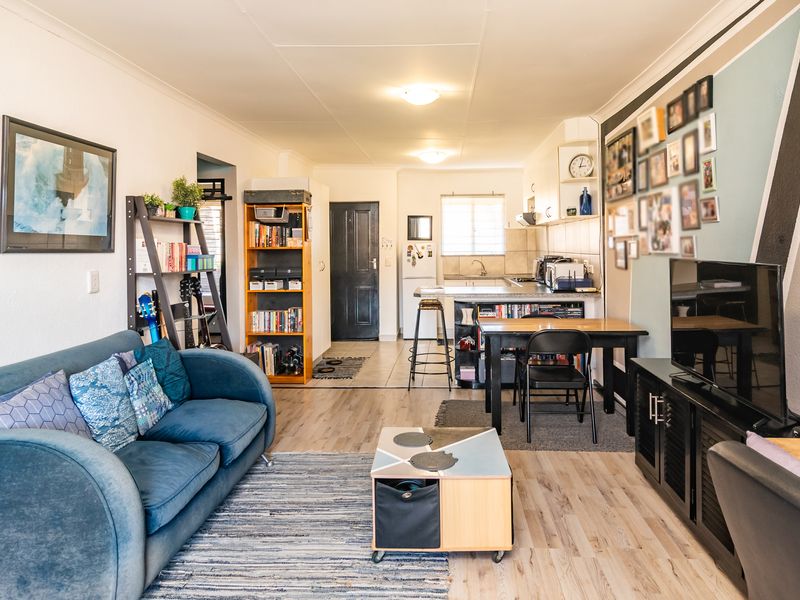Open-plan living area featuring a combined lounge and kitchen space with laminate flooring and functional cabinetry.