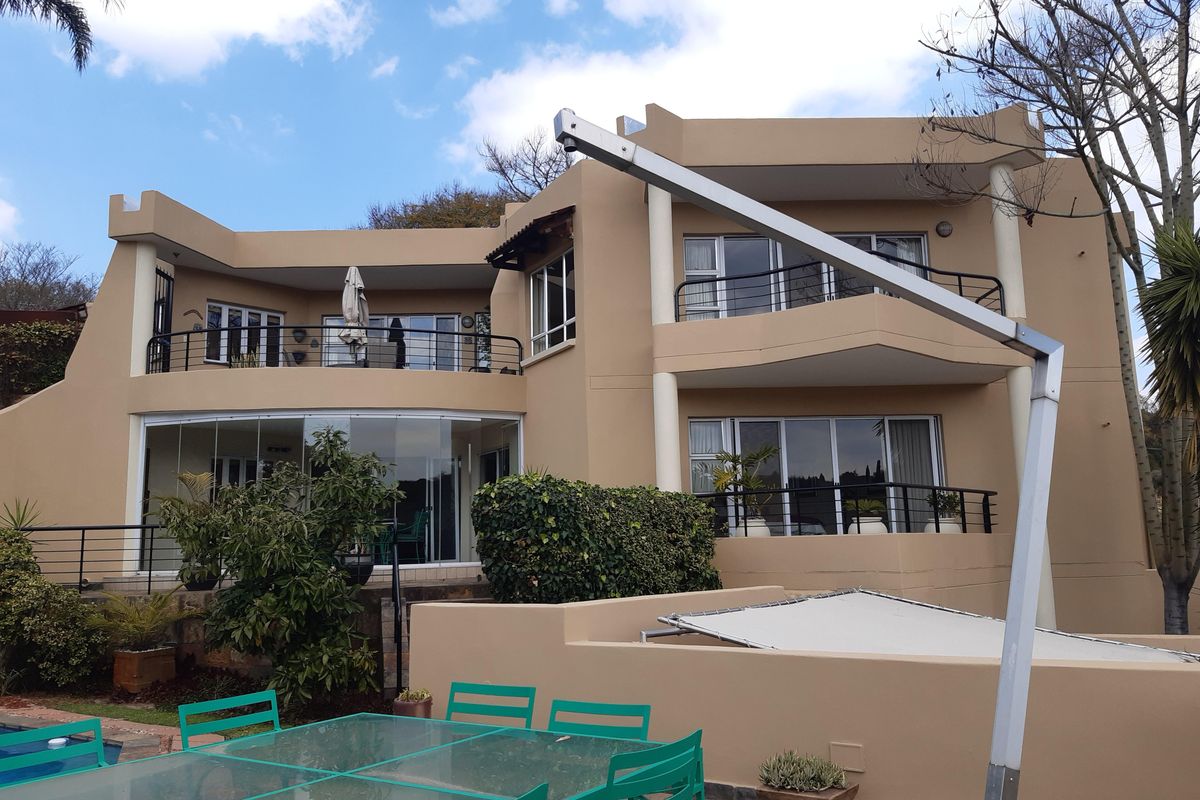 Rear view of a multi-story residential property featuring balconies, sliding glass doors, and a paved patio area.