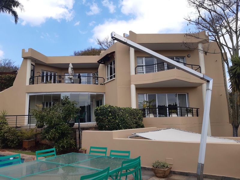 Rear view of a multi-story residential property featuring balconies, sliding glass doors, and a paved patio area.
