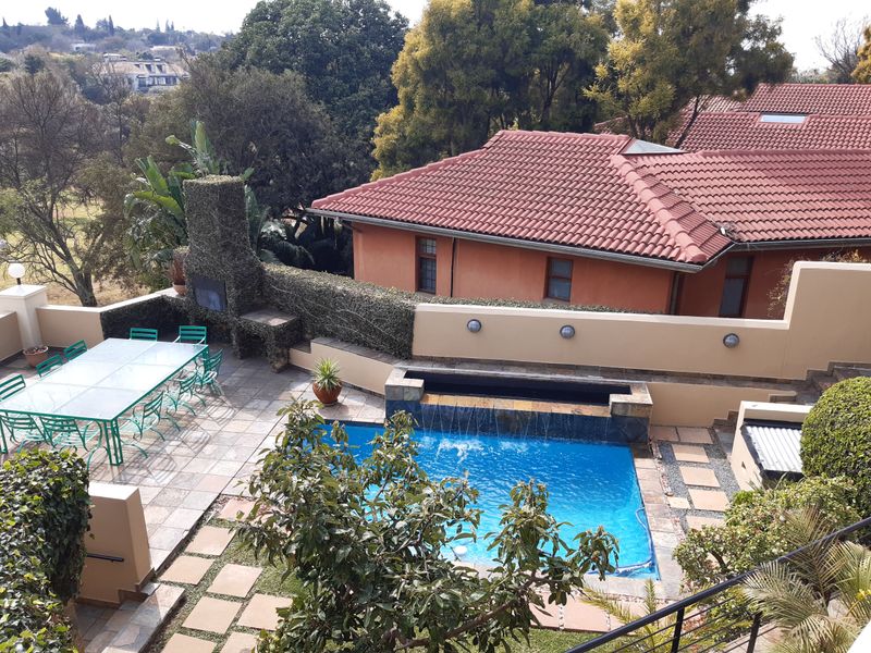 Outdoor pool area featuring a built-in braai, water feature, and paved patio space, set within a private garden environment.