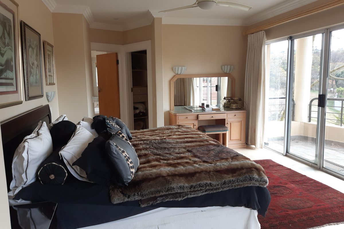Spacious bedroom featuring a built-in vanity, walk-in closet, ceiling fan, and large sliding glass doors opening to a private balcony.