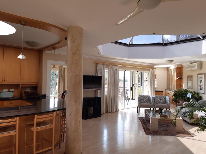 Spacious open-plan living and kitchen area featuring a large skylight, granite countertops, and sliding doors leading to an outdoor space.