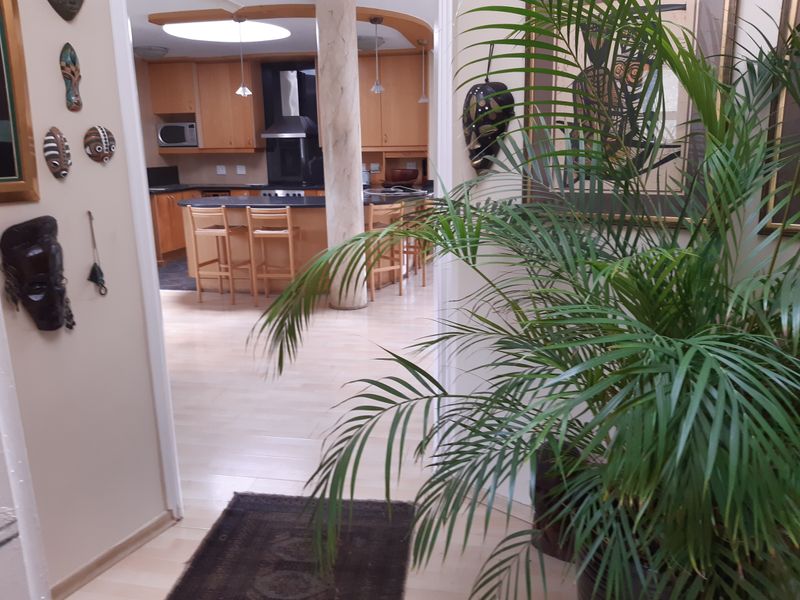 A view from the hallway into a kitchen featuring wooden cabinetry, a central island, and integrated appliances.
