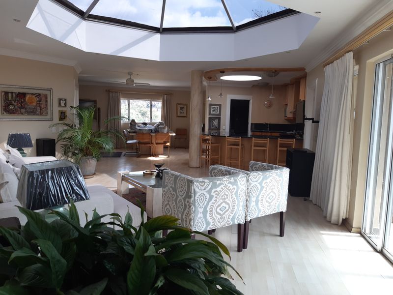 Spacious open-plan living and kitchen area featuring a large central skylight, laminate flooring, and direct access to outdoor space through sliding glass doors.