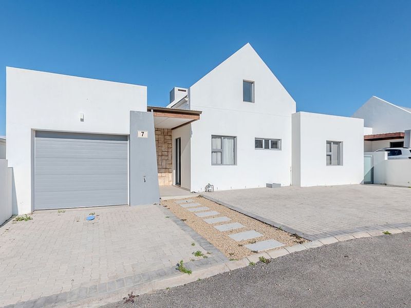 Modern white facade featuring a single garage, paved driveway, stone accent wall, and clean architectural lines.