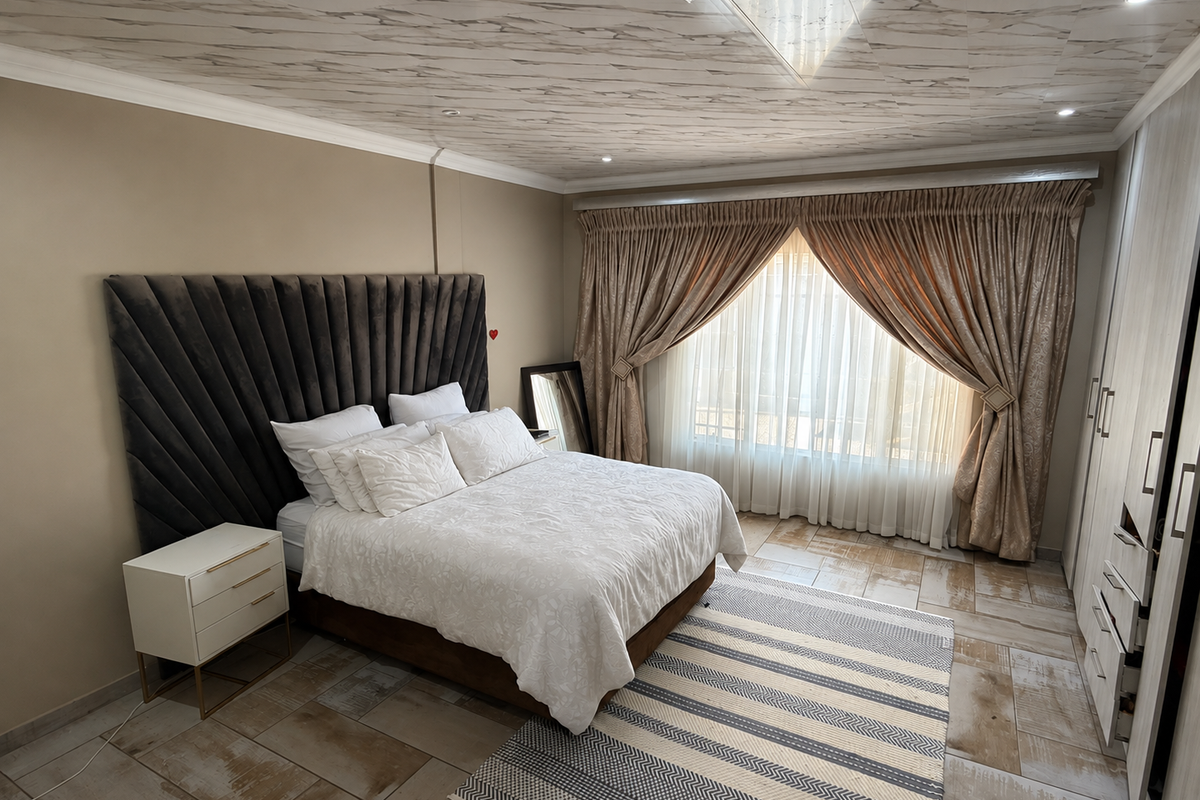 A well-maintained bedroom featuring tiled flooring, built-in wardrobes, and a decorative ceiling with recessed lighting.