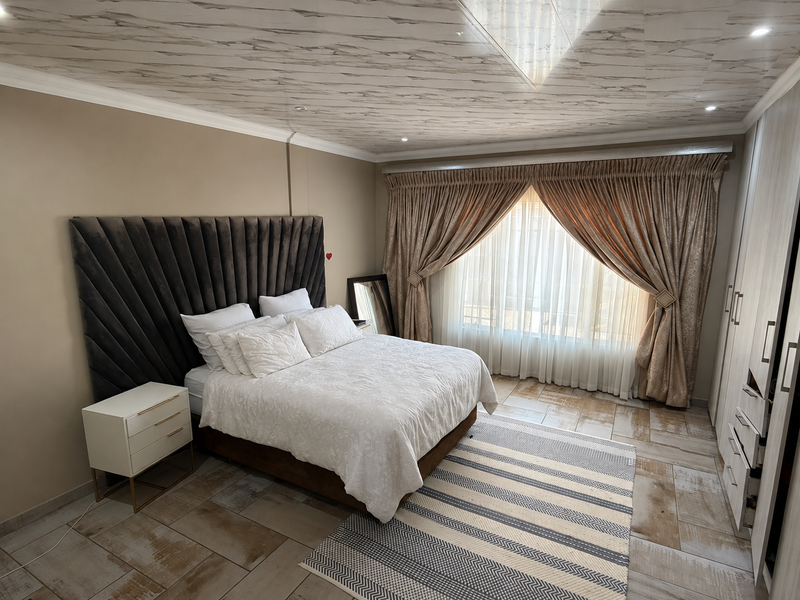 A well-maintained bedroom featuring tiled flooring, built-in wardrobes, and a decorative ceiling with recessed lighting.