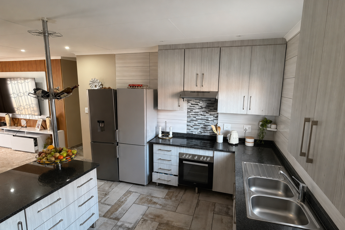 Modern kitchen featuring light wood-grain cabinetry, dark granite countertops, stainless steel appliances, and a functional island layout with tiled flooring.