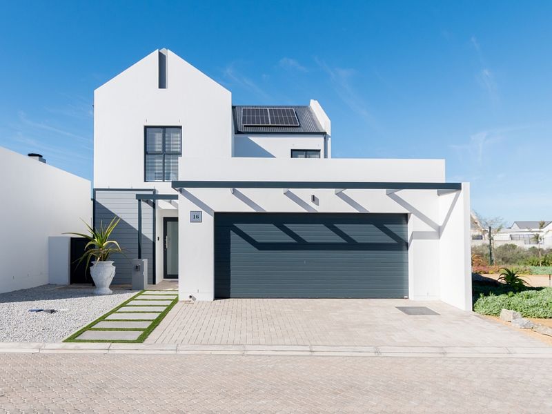 Modern two-story residential home featuring a clean white facade, integrated garage, solar panels, and a paved driveway with a landscaped walkway.
