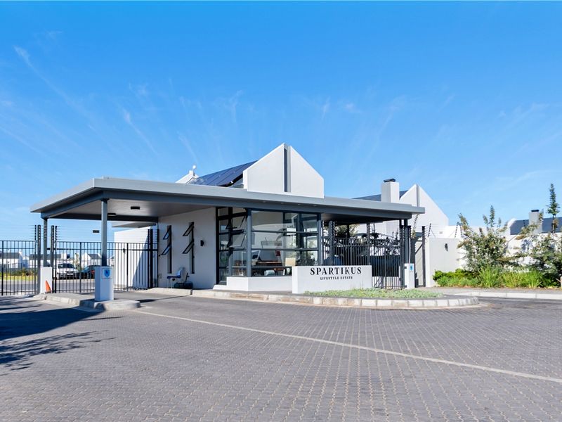 The secure entrance gatehouse of Spartikus Lifestyle Estate, featuring modern architecture, paved driveway, and integrated security systems.