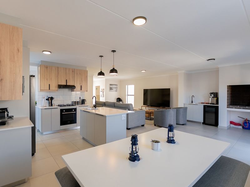 Modern open-plan living area featuring a contemporary kitchen with stone countertops, built-in appliances, and a spacious dining area with a built-in fireplace.