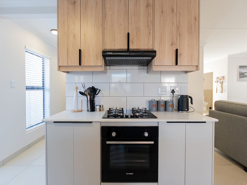 Modern kitchen featuring light wood cabinetry, white subway tile backsplash, quartz countertops, and integrated Bosch oven and gas hob.