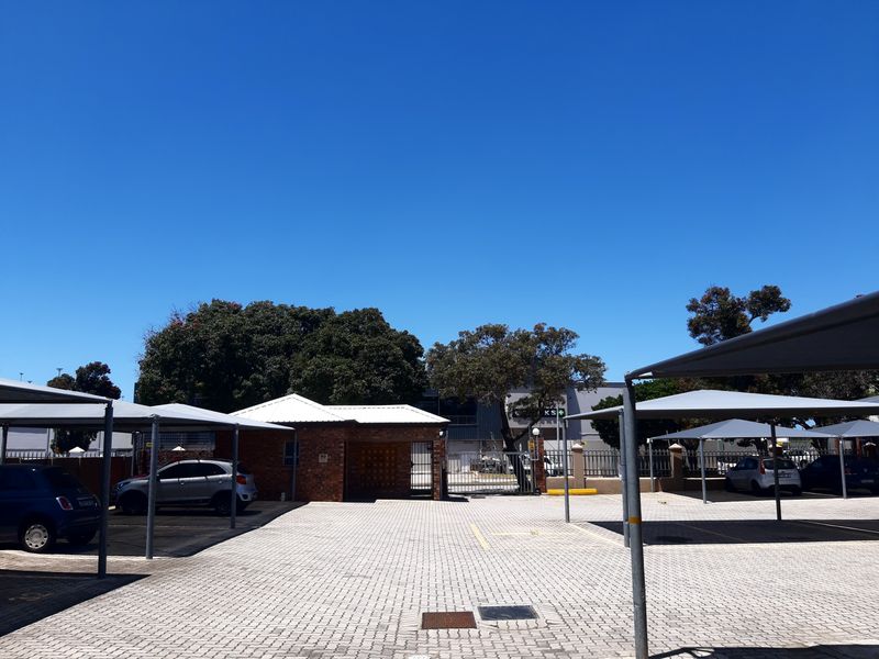 Outdoor parking area featuring paved driveway and multiple shade cloth carports within a secure complex.