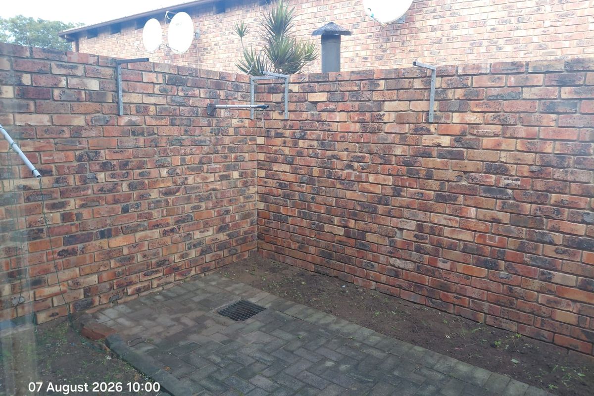 A private rear courtyard area featuring brick boundary walls, paved flooring, and drainage, offering a functional outdoor space.