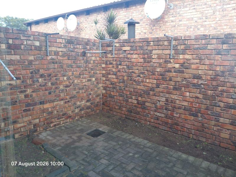A private rear courtyard area featuring brick boundary walls, paved flooring, and drainage, offering a functional outdoor space.
