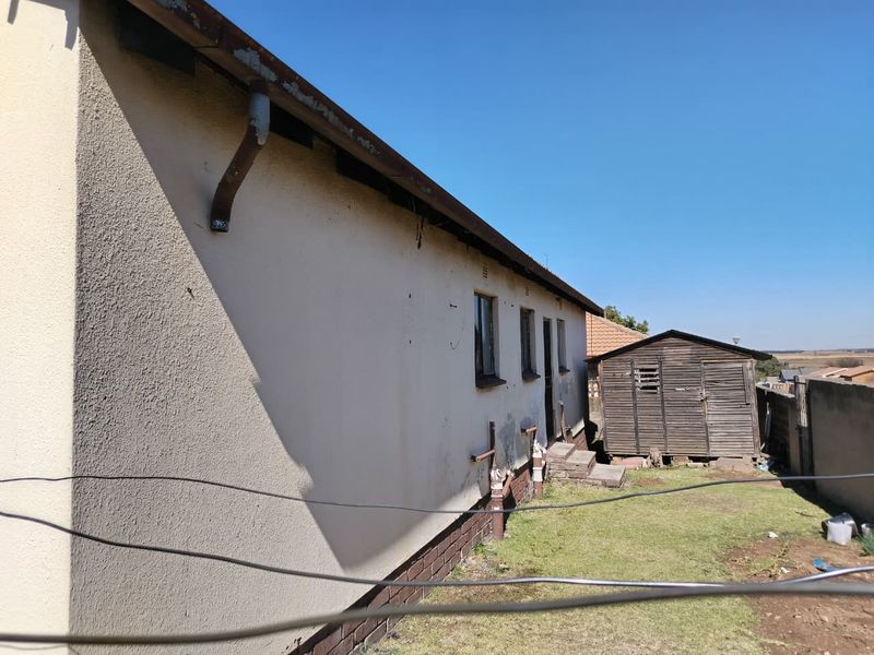 Rear exterior view of the property showing the building facade, guttering, and a small garden area with a wooden shed.