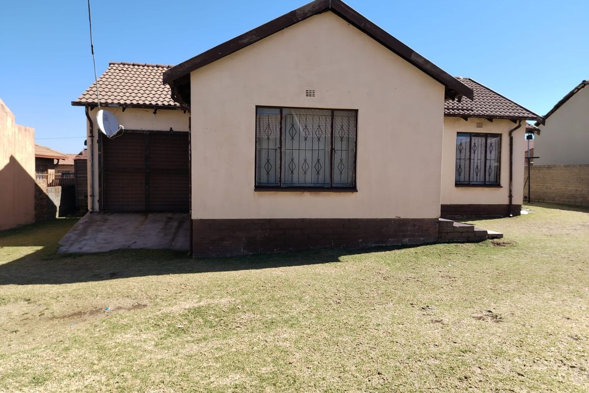 Rear view of a detached house featuring a tiled roof, security bars on windows, and an attached garage with a concrete driveway.