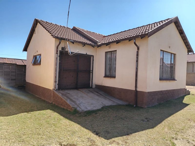Front elevation of a single-story house featuring a tiled roof, concrete driveway, and integrated garage with security bars on the windows.
