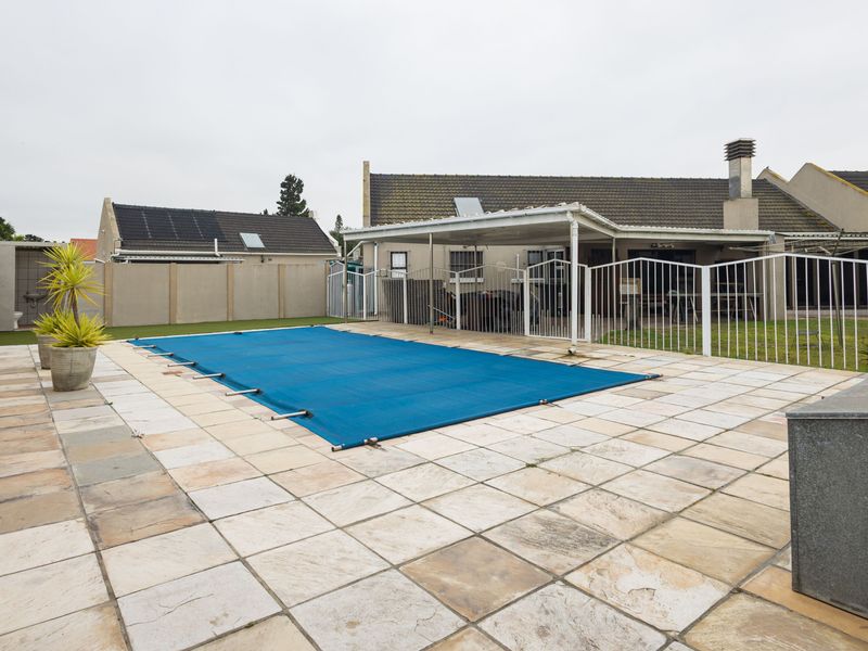 Outdoor pool area featuring a paved patio, metal safety fencing, and a covered patio space attached to the main residence.