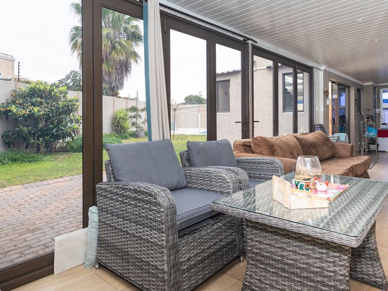 A spacious enclosed patio featuring tiled flooring and large aluminum sliding doors that provide seamless access to the rear garden area.