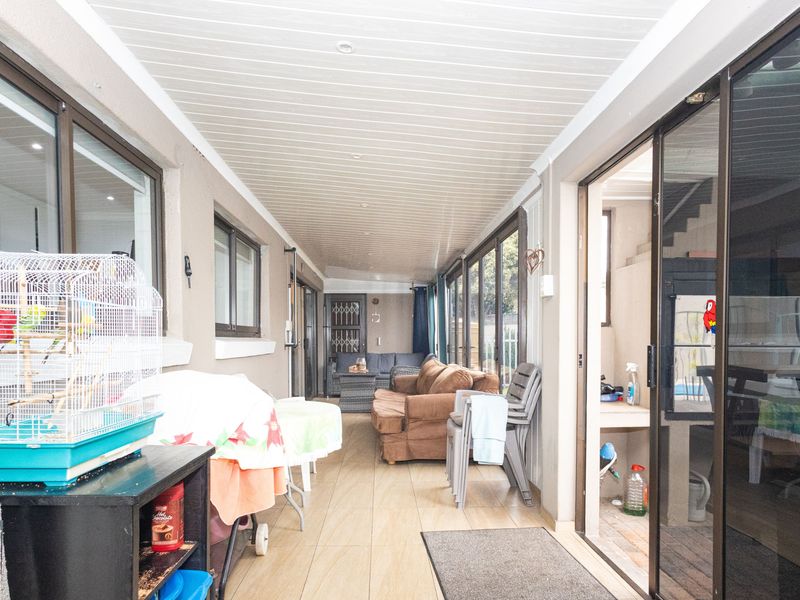 A covered patio area featuring tiled flooring, recessed ceiling lights, and multiple sliding glass doors providing access to the interior living spaces.