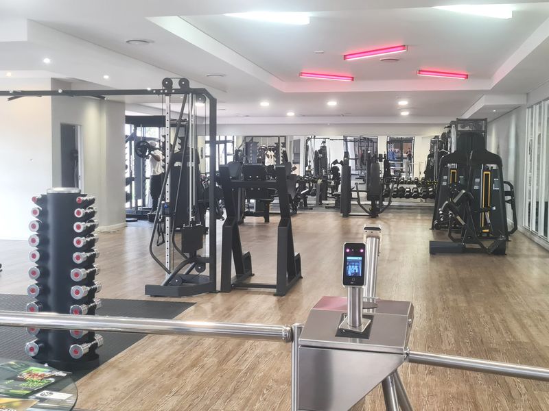 A well-maintained, modern apartment complex gym facility featuring professional-grade exercise equipment, mirrored walls, and secure access control.