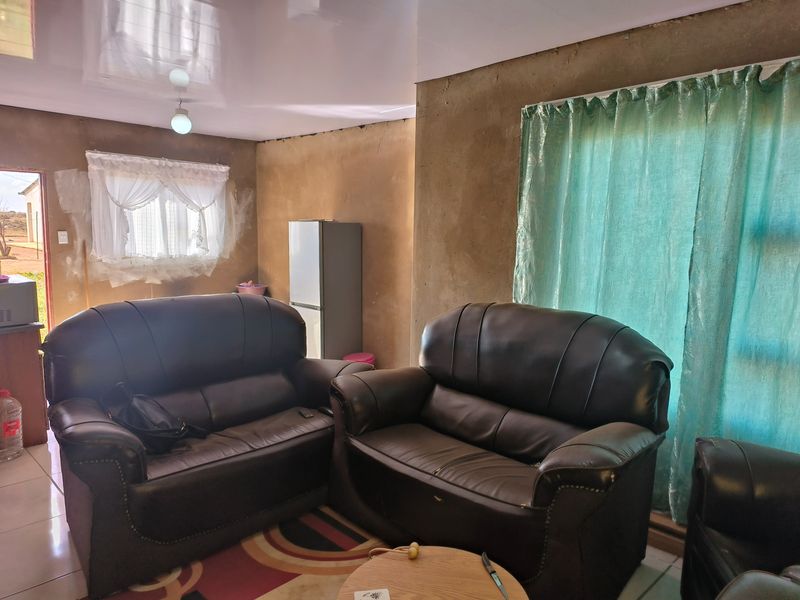 A living room area featuring tiled flooring and a glossy ceiling, currently requiring wall finishing and plastering to complete the interior aesthetic.