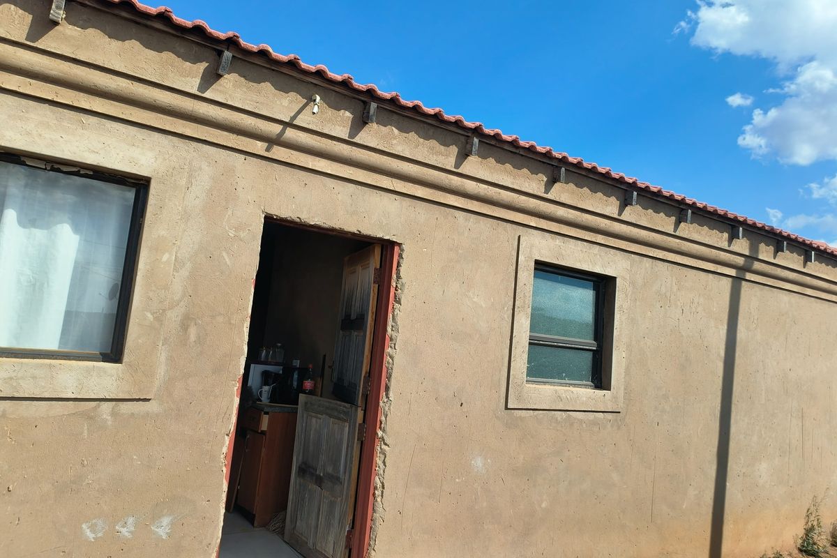 Exterior view of a single-story dwelling featuring plastered walls, terracotta roof tiles, and a timber entrance door.