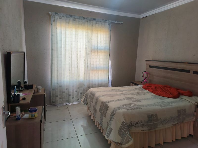 A bedroom featuring tiled flooring and neutral wall finishes, offering a functional space with potential for cosmetic updates.