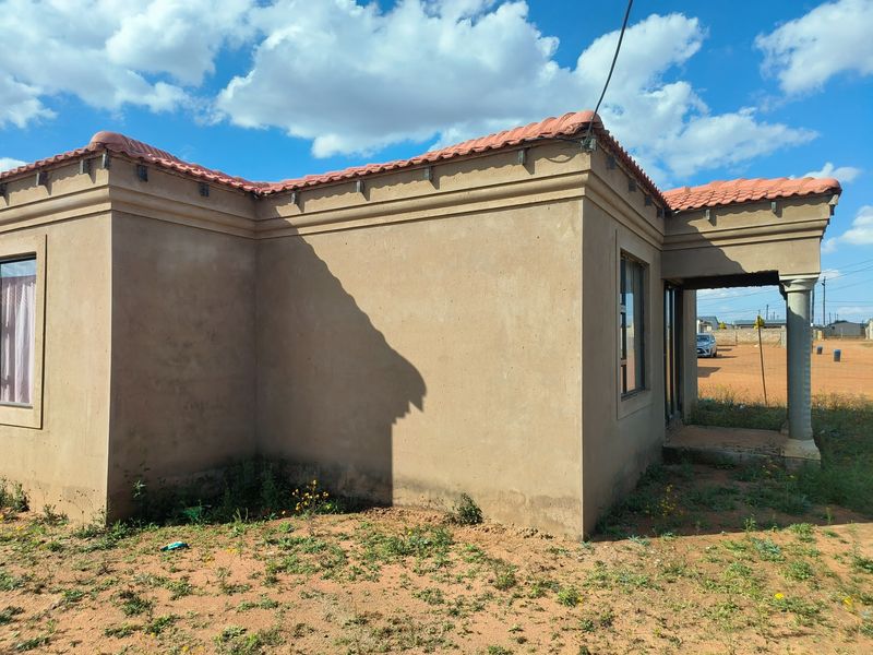 A single-story residential property featuring plastered exterior walls, a terracotta tiled roof, and a covered entrance porch with a concrete column.