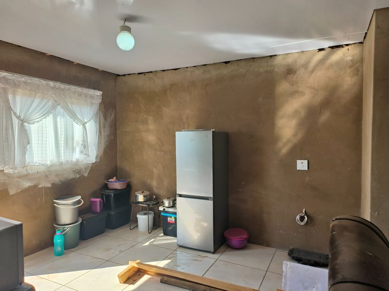 An unfinished kitchen space featuring tiled flooring and basic electrical infrastructure, requiring significant renovation and cabinetry installation to become a functional culinary area.