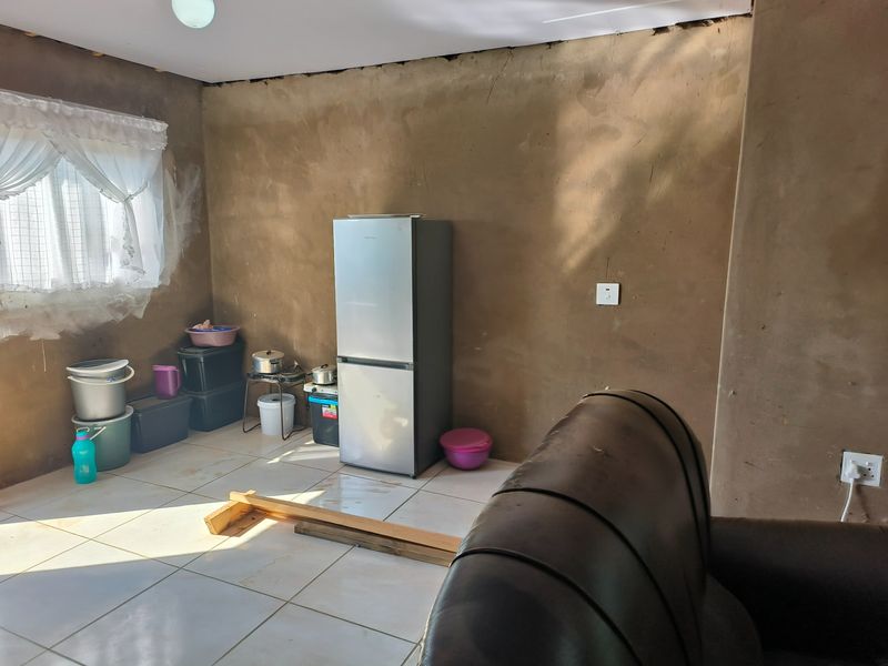 A living area featuring tiled flooring and unfinished wall surfaces, requiring cosmetic attention and finishing to improve the overall aesthetic and condition.