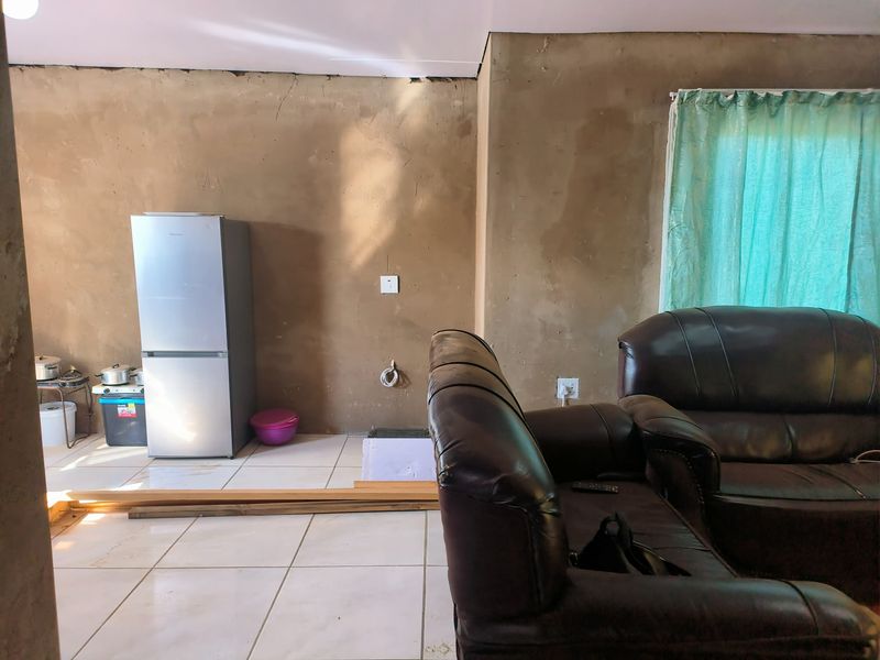 Open plan living area featuring tiled flooring and unfinished plastered walls, offering a blank canvas for renovation and interior finishing.