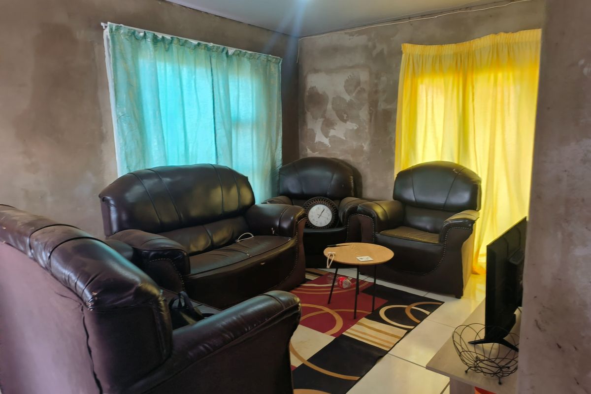 A living room area featuring tiled flooring and unfinished plaster walls, offering a blank canvas for renovation and interior finishing.
