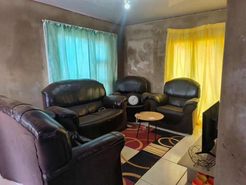 A living room area featuring tiled flooring and unfinished plaster walls, offering a blank canvas for renovation and interior finishing.