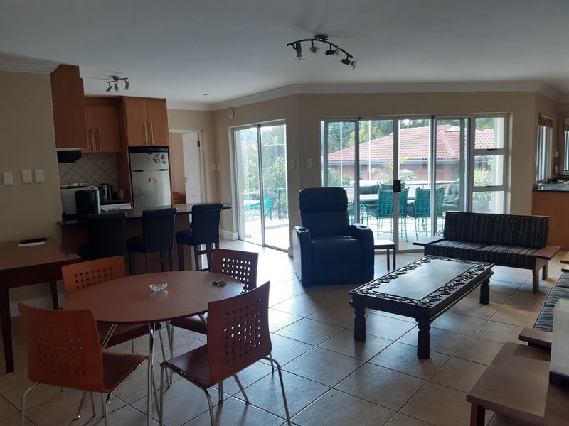 Spacious open-plan living and dining area featuring tiled floors, a functional kitchen with island seating, and large sliding doors leading to an outdoor patio.