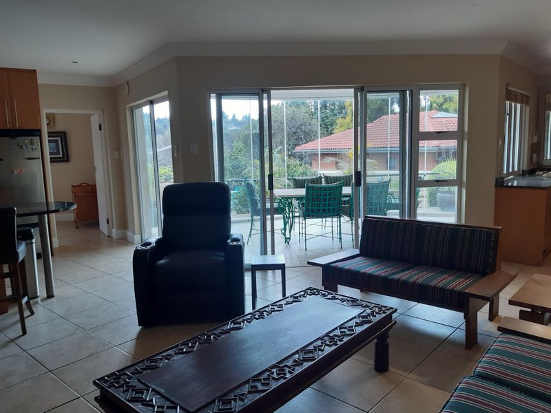 Open-plan living area featuring tiled floors, built-in kitchen cabinetry, and large sliding glass doors providing access to an outdoor patio area.