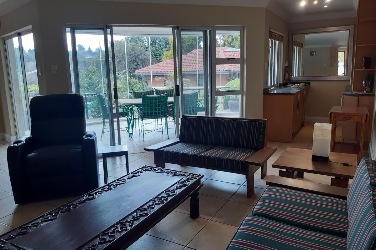 Spacious open-plan living area featuring tiled floors, built-in cabinetry, and large sliding glass doors providing access to an outdoor patio.