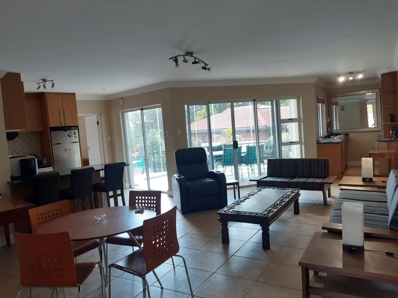 Spacious open-plan living area featuring a kitchen with island, tiled flooring, and large sliding glass doors providing access to the outdoor patio.