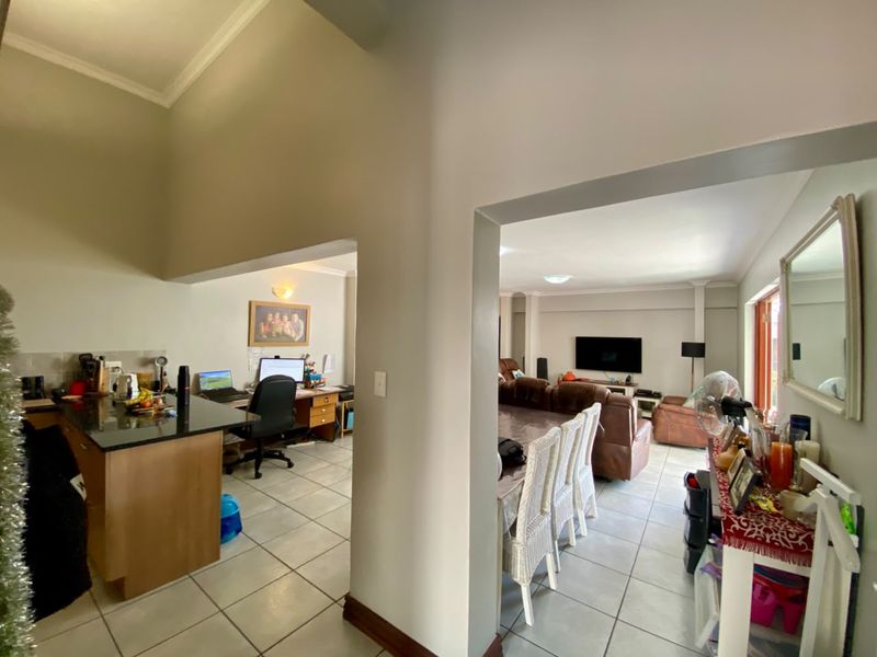Open plan living area featuring tiled flooring, a kitchen island with granite countertops, and a spacious layout connecting the kitchen and lounge.