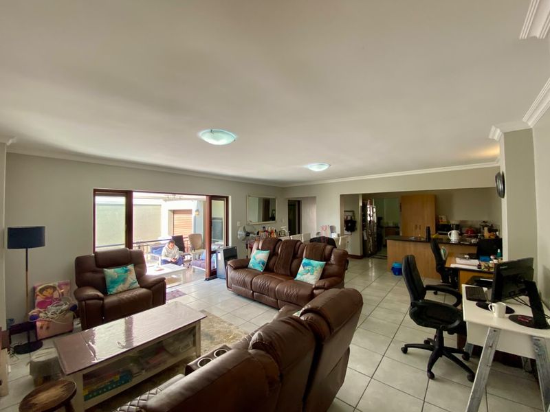 Spacious open-plan living area featuring tiled flooring, coved ceilings, and seamless flow to an outdoor patio through large sliding glass doors.