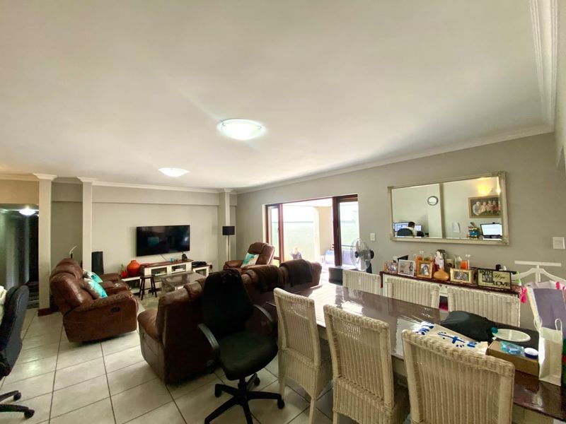 Spacious open-plan living and dining area featuring tiled flooring, neutral walls, and large sliding glass doors providing access to the outdoor patio.
