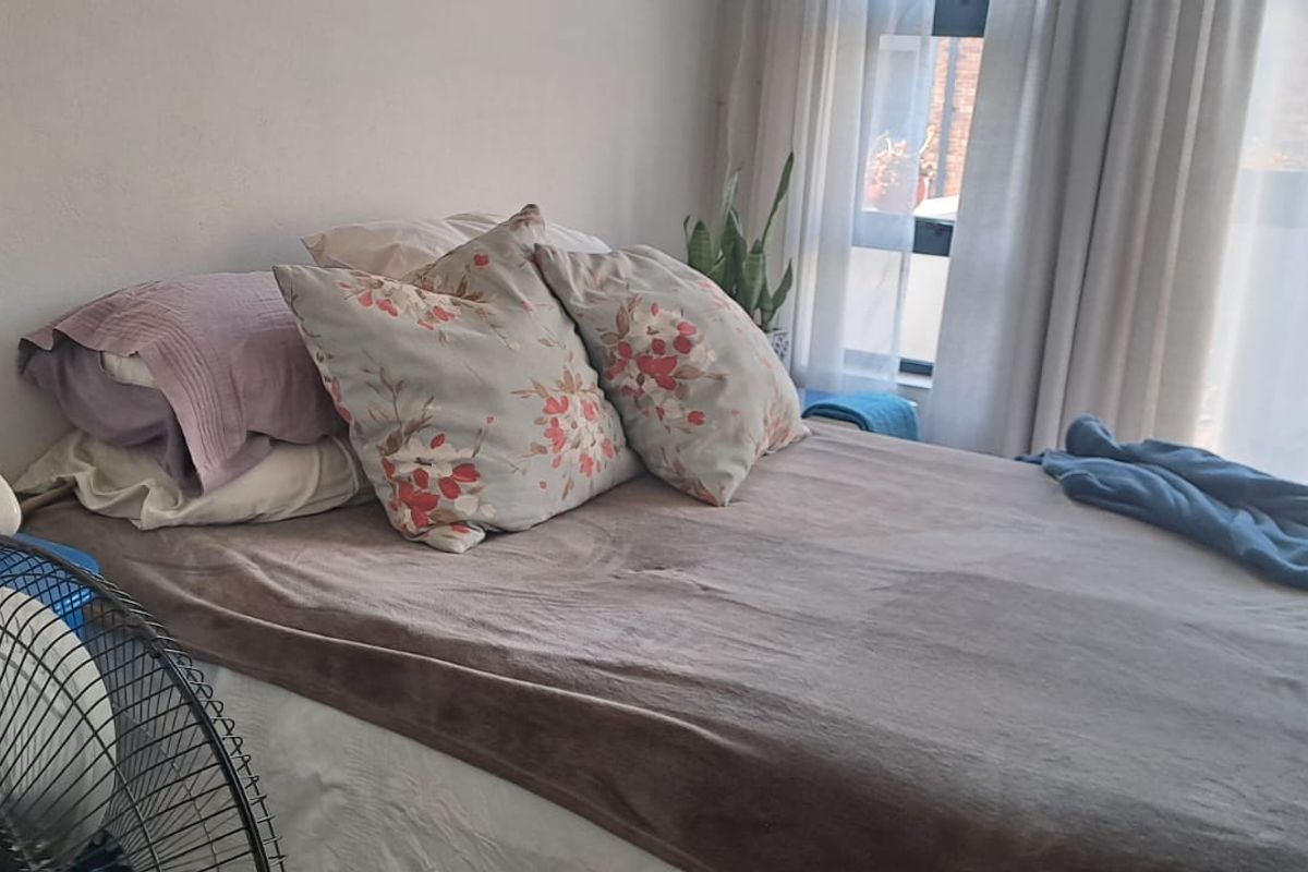 A bedroom featuring a large window with natural light and curtain tracks, providing a bright and functional living space.