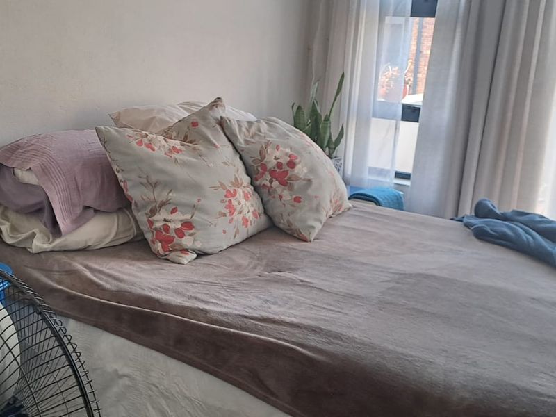 A bedroom featuring a large window with natural light and curtain tracks, providing a bright and functional living space.