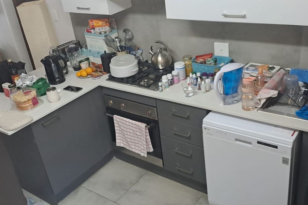 A functional kitchen featuring modern grey cabinetry, stone countertops, a gas hob, built-in oven, and an integrated dishwasher.