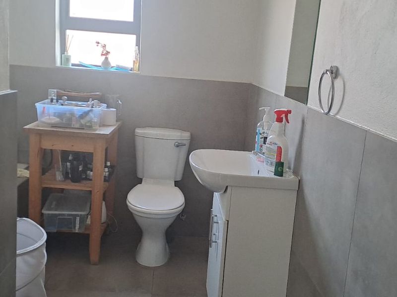 A functional bathroom featuring a standard toilet, vanity basin, and neutral wall tiling, providing a clean and practical space.