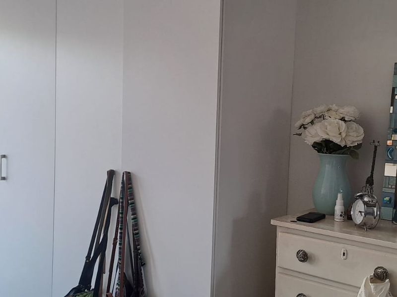A bedroom featuring a clean, white built-in wardrobe and neutral wall finishes, providing ample storage space.