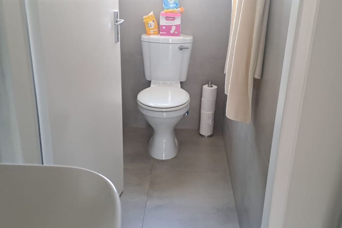 A compact bathroom featuring neutral wall and floor tiles with a standard white toilet suite.